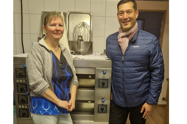 Inhaberin Valeria Ortner und B&uuml;rgermeister Markus Hollemann vor einer K&uuml;chenmaschine