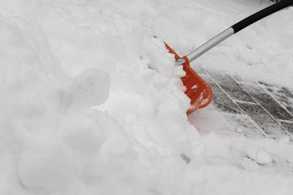 Orange Schneeschaufel schiebt Schnee weg