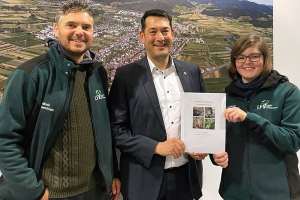 Lisa Gollent, Trainee am Forstamt Emmendingen (rechts) und Förster Bernd Nold (links) überreichen das Ökologische Vorsorgekonzept Gemeindewald Denzlingen an Bürgermeister Markus Hollemann (mitte).