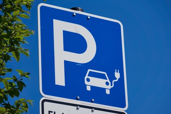 Blaues Schild mit weißer Schrift und weißer Zeichnunf eines Elektroautos