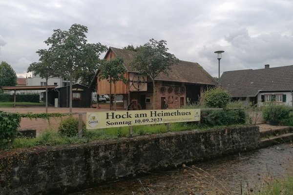 Blick auf den Banner mit der Aufschrift "Hock am Heimethues Sonntag, 10.09.2023", angebracht am Glottergeländer, im Hintergrund die Museumsscheune