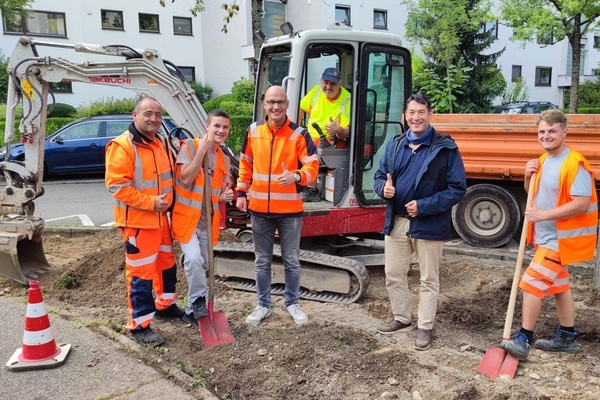 Sechs Mnner auf einer Baustelle. Einer der Mnner sitzt in einem Bagger