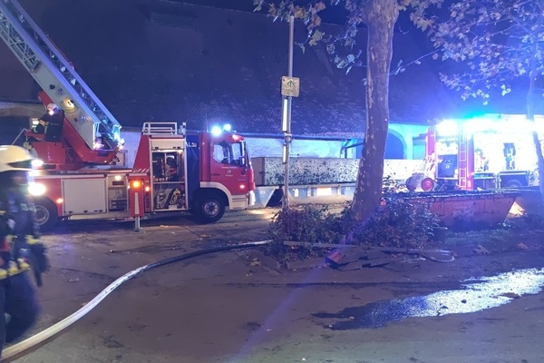 Zwei L&ouml;schfahrzeuge und eine Einsatzkraft vor einem Geb&auml;ude