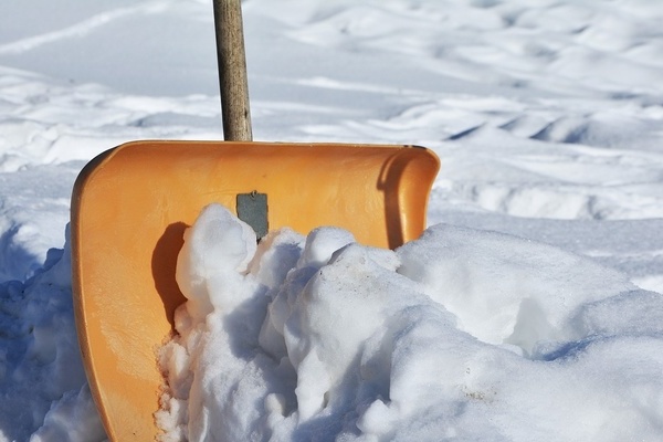 Weier Schnee und eine orangefarbene Schneeschaufel