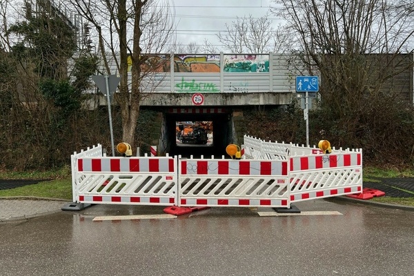 Rot weiße Absperrung vor einer Bahnunterführung; im Hintergund Baugerät