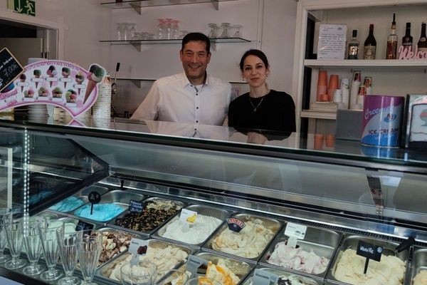 Bürgermeister Hollemann und Frau Güler Cicco-Sander, Inhaberin der Eisdiele, stehen hinter der mit verschiedenen Eissorten gefüllten Eistheke