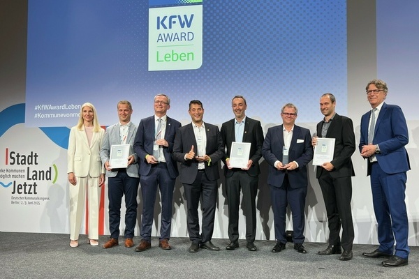 Der Denzlinger Bürgermeister Markus Hollemann (Mitte l.) u Kämmerer Martin Ziegler (Mitte r.) repräsentieren Denzlingen bei d. Verleihung d. KfW Awards Leben 2025. Links: KfW-Vorständin Melanie Kehr, rechts Stefan Wintels, Vorstandsvorsitzender der KfW