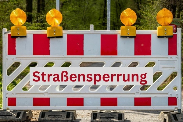 Straßensperrung - rote Schrift auf weißem Untergrund und Verkehrsabsperrung mit organgenen Warnleuchten